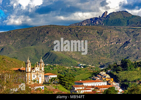 Vista di una delle numerose chiese e le tue torri di stile barocco e architettura coloniale della città di Ouro Preto Minas Gerais con le sue montagne in t Foto Stock