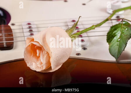 Rosa con gocce di rugiada su chitarra elettrica. Close up, il fuoco selettivo Foto Stock