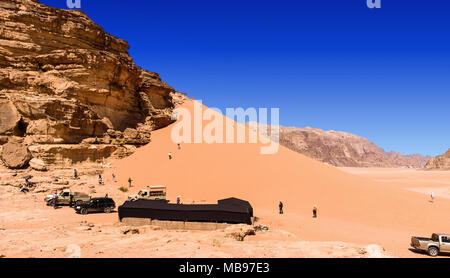 Wadi Rum, Giordania, Marzo 8, 2018: Turisti che hanno guidato attraverso il deserto della riserva in jeep e suv salire sulla rossa grande duna di sabbia in Foto Stock