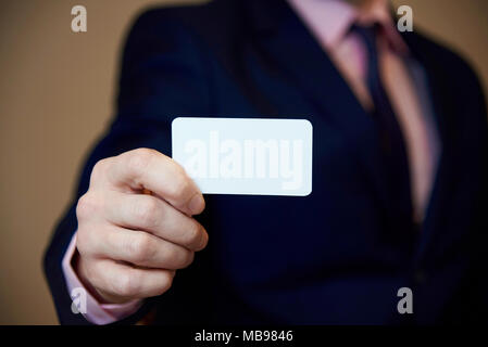 Un bianco blank business card nella mano di un giovane uomo in un business suit. Foto Stock