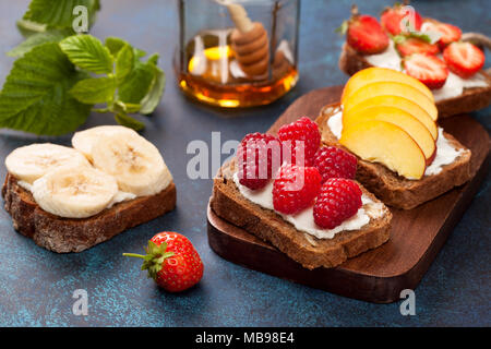 La dieta la prima colazione. Toast con crema di formaggio e frutti di bosco freschi e frutta: banana, lampone, mirtillo, fragola, pesca. Foto Stock