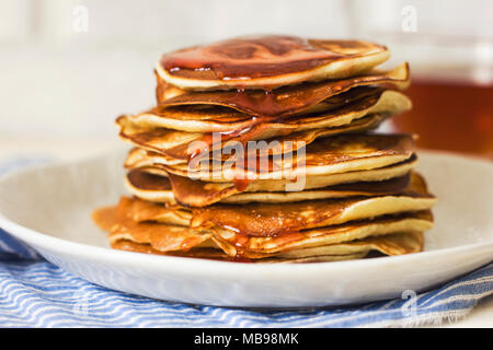 Pancake fatti in casa versato gocce di sciroppo in piastra bianca, primo piano Foto Stock