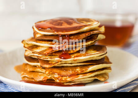 Pancake fatti in casa versato gocce di sciroppo in piastra bianca, primo piano Foto Stock