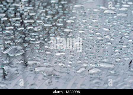 Ripiano in vetro tavolo da giardino dopo una pioggia pesante doccia. Goccioline di acqua sul vetro. Foto Stock