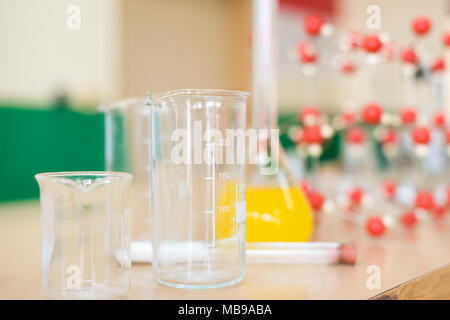 Vetreria chimica con liquido di formula e struttura molecolare modello presso la scienza in aula banco da laboratorio. Foto Stock
