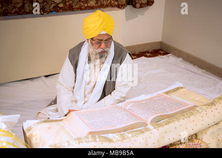 Sacerdote Sikh, un Granthi, lettura Sri Guru Granth Sahib, che è il libro santo in sikhismo. In Richmond Hill Queens, a New York. Foto Stock