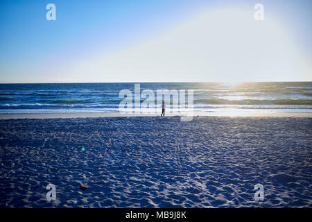 Lone uomo a camminare sulla spiaggia di Anna Maria Island , Florida , al tramonto con impronte nella sabbia e una riflessione sull'acqua Foto Stock