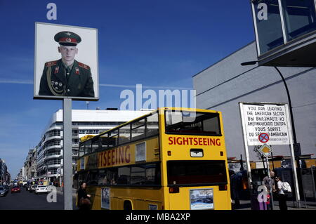 Berlino, Germania. Xx Apr, 2015. Un giallo bus turistico passa una scatola di luce con un ritratto di un soldato sovietico al Checkpoint Charlie sulla Friedrichstrasse in Berli, raffigurata sul 20 aprile 2015. - Nessun filo - SERVIZIO | Utilizzo di credito in tutto il mondo: dpa/Alamy Live News Foto Stock