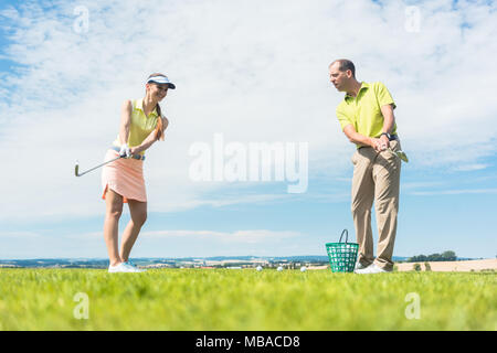 Giovane donna pratica la mossa corretta durante il golf di classe Foto Stock