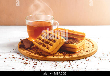 Waffles fatti in casa con la marmellata sul vecchio tavolo in legno. Wafers con tazza di tè, teiera, cioccolato. Foto Stock