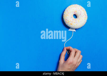 Ciambella sul blu, Cucina Creativa il minimalismo, la ciambella in forma di palloncino al cielo, vista dall'alto con spazio copia, tonica Foto Stock