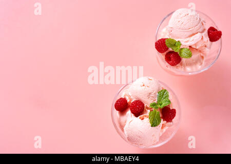 Vista dall'alto di rasberry gelati di palline in piatti in vetro su sfondo rosa Foto Stock