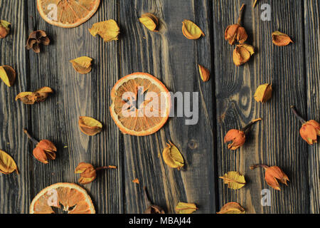 Fettine di arancia e petali di fiori secchi su sfondo di legno Foto Stock