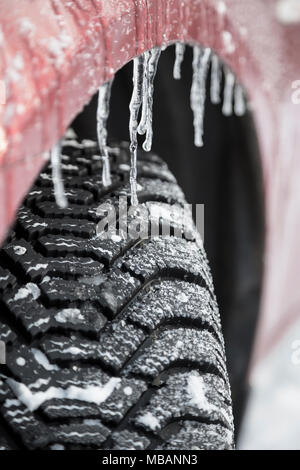 Battistrada di pneumatici invernali con prigionieri e ghiaccioli sulla ruota di un automobile Foto Stock