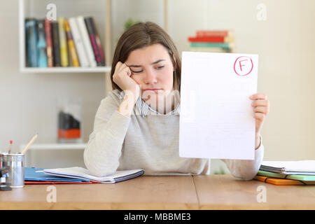 Triste studente mostrando un esame non superato alla telecamera a casa Foto Stock