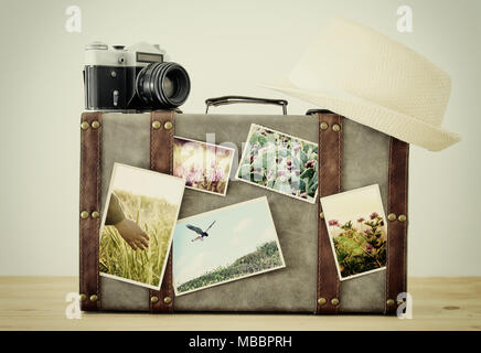Immagine di un vecchio vintage bagagli, fedora hat e vintage vecchia foto fotocamera con la natura le foto su un pavimento in legno Foto Stock