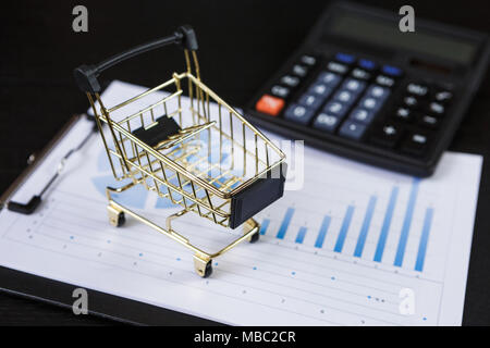 I carrelli della spesa con la calcolatrice sul grafici finanziari Foto Stock