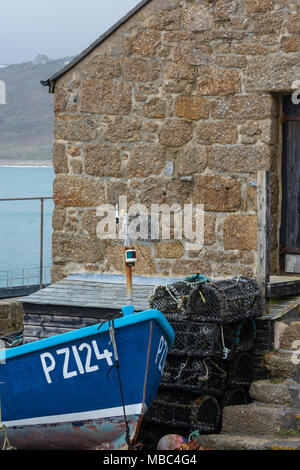 Un vecchio open barca a remi o in barca da pesca di fronte a un vecchio in pietra o boathouse fishermans hut sul Cornish Coast a sennett cove vicino al Lands fine. Foto Stock