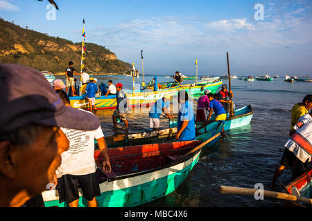 Puerto Lopez, Ecuador, Giugno 30, 2015: gruppo di pescatori con le loro barche di atterraggio sulla spiaggia in Puerto Lopez, a consegnare le loro catture ai commercianti di pesce Foto Stock