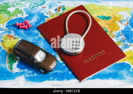 Il blocco di codice sul passaporto rosso, giocattolo auto, le puntine sulla mappa del mondo sullo sfondo. Concept-Ban su viaggi, mancanza di Visa. Foto Stock