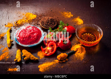 Close up di pomodoro,con la sua purea,miele,curcuma in polvere di legno di sandalo,e la curcuma in polvere sulla superficie di legno in stile gotico scuro colori per meglio e hea Foto Stock