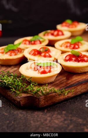 Mini crostate con Pomodorini con Mozzarella su tavola di legno. Foto Stock