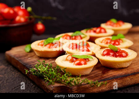 Mini crostate con Pomodorini con Mozzarella su tavola di legno. Foto Stock