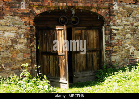 Un vecchio fienile porta su una strada rurale in Sierpnica, Polonia. Foto Stock