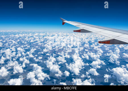 Ala di un aereo commerciale sorvolando soffice bianco nuvole cumulus, Australia Foto Stock