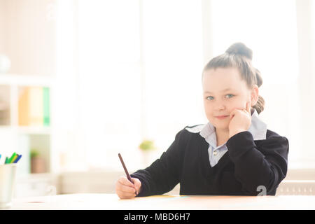 Ritratto di bella schoolgirl seduto alla scrivania e disegno Foto Stock