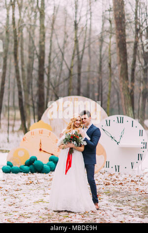 Happy sposi in posa a grandi orologi vintage in autunno foresta. Decorazioni Creative Foto Stock