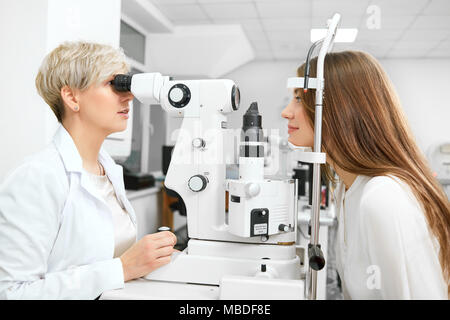 Foto di esperti , expirienced oculista controllo paziente la visione in laboratorio. contribuendo a risparmiare e a migliorare la salute degli occhi e visione. Indossando bianco uniforme, cercando professinal. Foto Stock