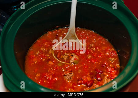 Servendo il peperoncino cotta da un tegame di coccio con un mestolo Foto Stock