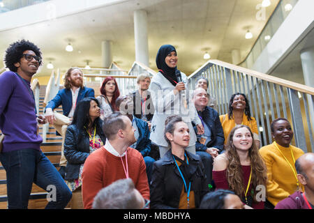 Donna sorridente in hijab parlando con microfono in udienza di conferenza Foto Stock