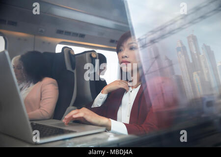 Focalizzato imprenditrice lavora al computer portatile sul treno passeggeri Foto Stock