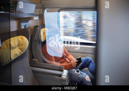 Giovane uomo utilizzando smart phone sul treno passeggeri Foto Stock