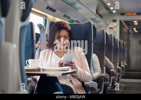 Imprenditrice di lavoro e di ascolto di musica con cuffie e smart phone sul treno passeggeri Foto Stock