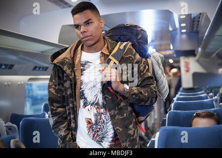 Giovane uomo con zaino imbarco treno passeggeri Foto Stock