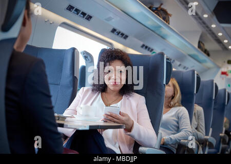 Ritratto sorridente, fiduciosi imprenditrice utilizzando smart phone sul treno passeggeri Foto Stock