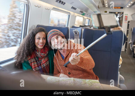 Felice coppia giovane tenendo selfie con selfie stick sul treno passeggeri Foto Stock