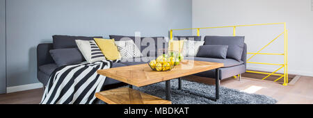 Agrumi sul tavolo di legno accanto a un angolo del lettino giallo con cuscino e coperta a strisce in living room interior Foto Stock