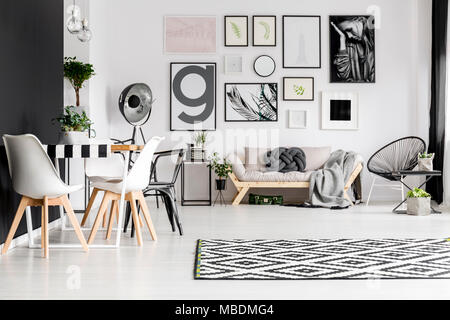 Galleria d'arte, tavolo da pranzo con sedie e un divano con coperta e cuscino del nodo in un bianco living room interior Foto Stock