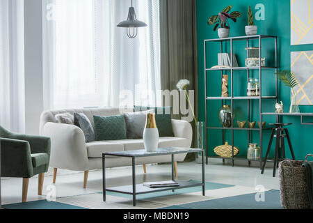 Poltrona verde accanto a un beige divano nel sofisticato salone interno con vaso sulla tabella Foto Stock