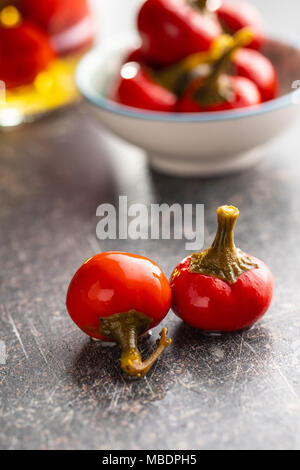 Decapare il peperoncino piccante. Verdure marinate sul vecchio tavolo da cucina. Foto Stock