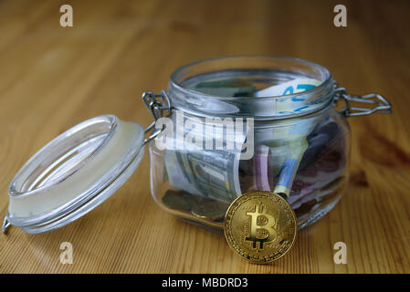 Denaro e jar bitcoin in esso. Mettere mano alle monete in vaso Foto Stock