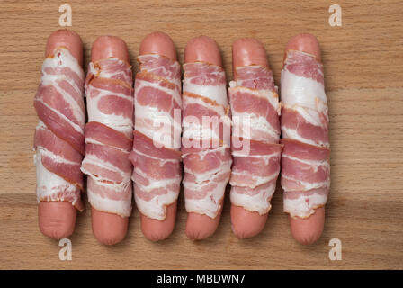 Preparazione di salumi crudi avvolto a spirale in pancetta su un sfondo di legno. Vista dall'alto. Foto Stock