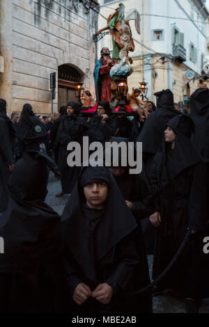 SESSA AURUNCA, Italia - 30 Marzo 2018 - La Easter Parade di cappucci neri camminando attraverso le strade di Sessa Aurunca, portando le statue dei Misteri della croce, Cristo morto e le tre Marie Foto Stock