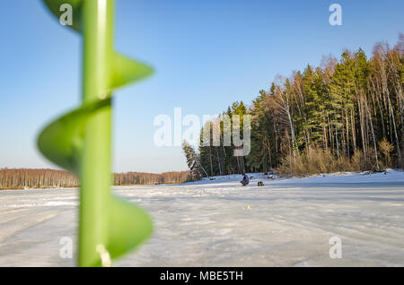 Un pescatore solitario sul ghiaccio del fiume Foto Stock