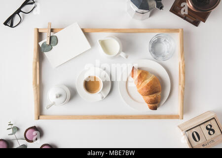 Lay piatto con tazza di caffè e croissant per la colazione sul vassoio sul tavolo bianco Foto Stock