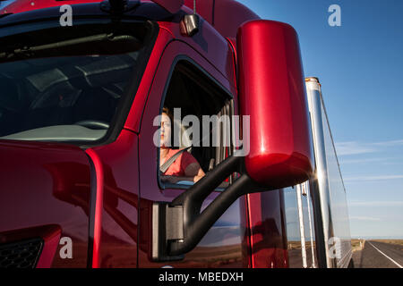 Vista di una donna caucasica conducente nella cabina del suo camion commerciali. Foto Stock